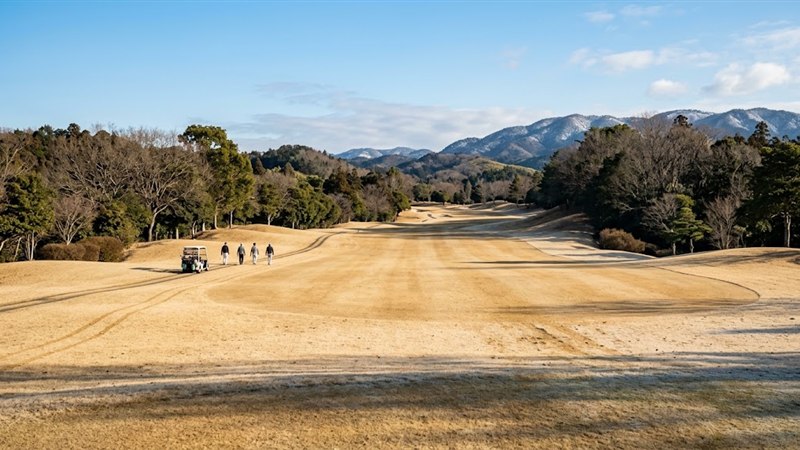 冬の晴れた週末、空いているフェアウェイを遠くの4人組がカートと歩いている