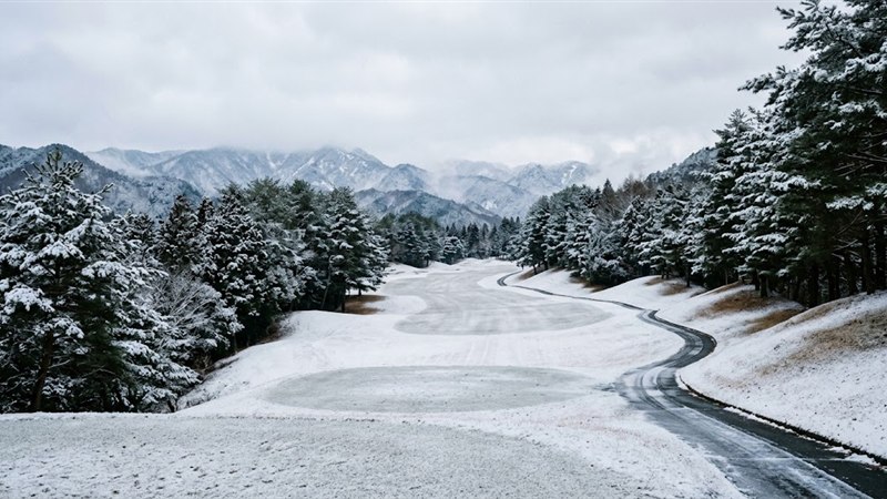 うっすら雪が積もった山間のゴルフ場のフェアウェイとカート道
