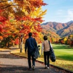紅葉に色づいたカート道を歩くゴルファーの夫婦