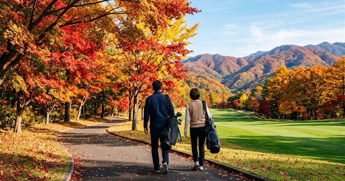 紅葉に色づいたカート道を歩くゴルファーの夫婦