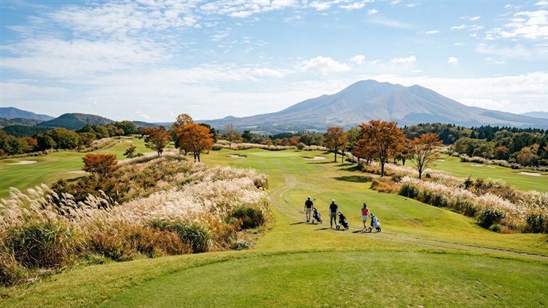 ススキが揺れる高原の紅葉ゴルフコースを歩く3人のゴルファー
